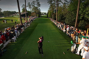 Tiger Woods mid-swing on the fairway at The Masters with a packed gallery lining the course HD wallpaper