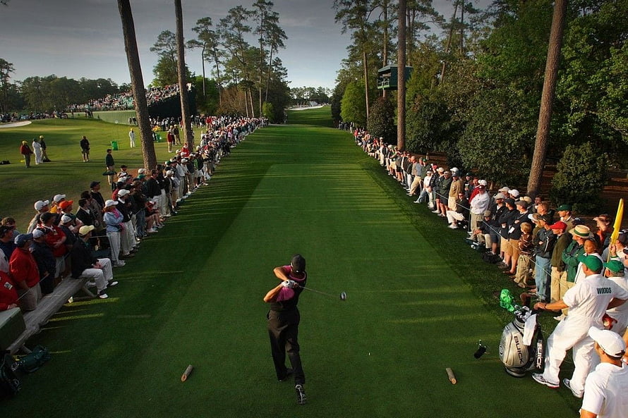 Tiger Woods mid-swing on the fairway at The Masters with a packed gallery lining the course HD wallpaper
