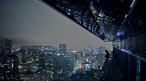 Silhouette of a person overlooking a sprawling urban skyline at night from a high-rise balcony HD wallpaper