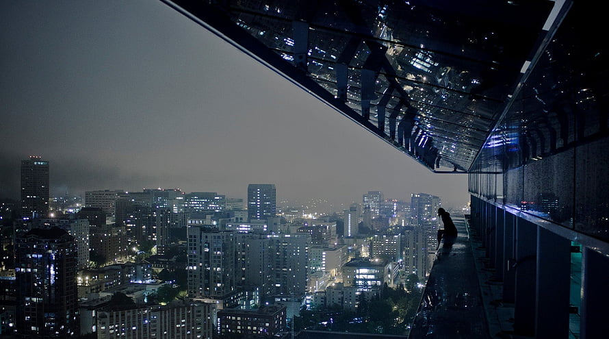 Silhouette of a person overlooking a sprawling urban skyline at night from a high-rise balcony HD wallpaper