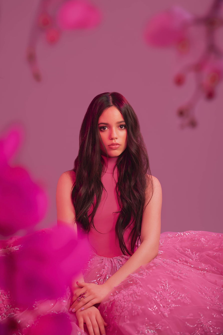 Jenna Ortega in a pink tulle gown surrounded by soft floral elements HD phone wallpaper