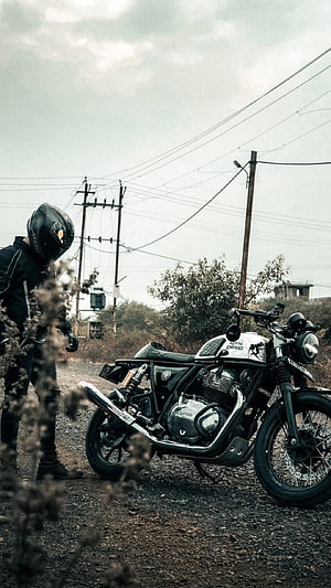 Royal Enfield Continental GT 650 parked on a gravel road with a rider in full gear HD phone wallpaper