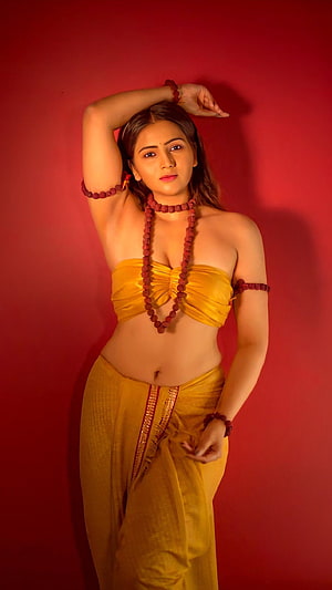 Sulekha Dahiya in a yellow traditional outfit with red beaded jewelry against a red background HD phone wallpaper