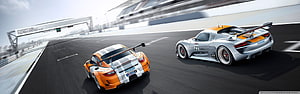 Two Porsche 918 Spyder race cars speeding on a professional circuit track HD wallpaper