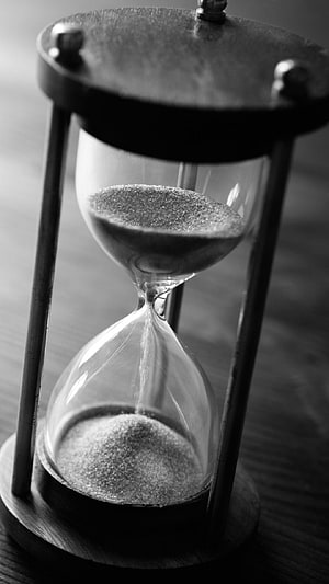Monochrome Close-Up of a Classic Wooden Hourglass with Falling Sand HD phone wallpaper