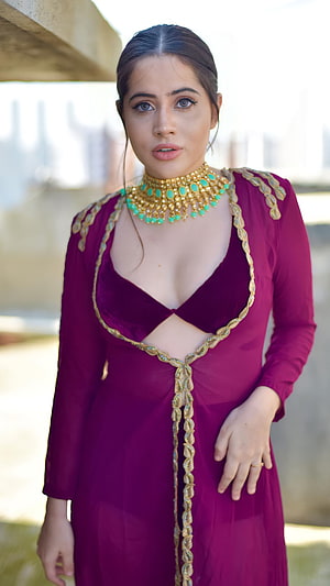 Urfi Javed in a deep purple gown with gold embroidery and turquoise statement necklace HD phone wallpaper
