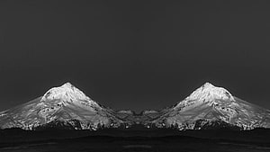 Monochrome Twin Snow-Capped Mountain Peaks Under a Dark Sky HD wallpaper