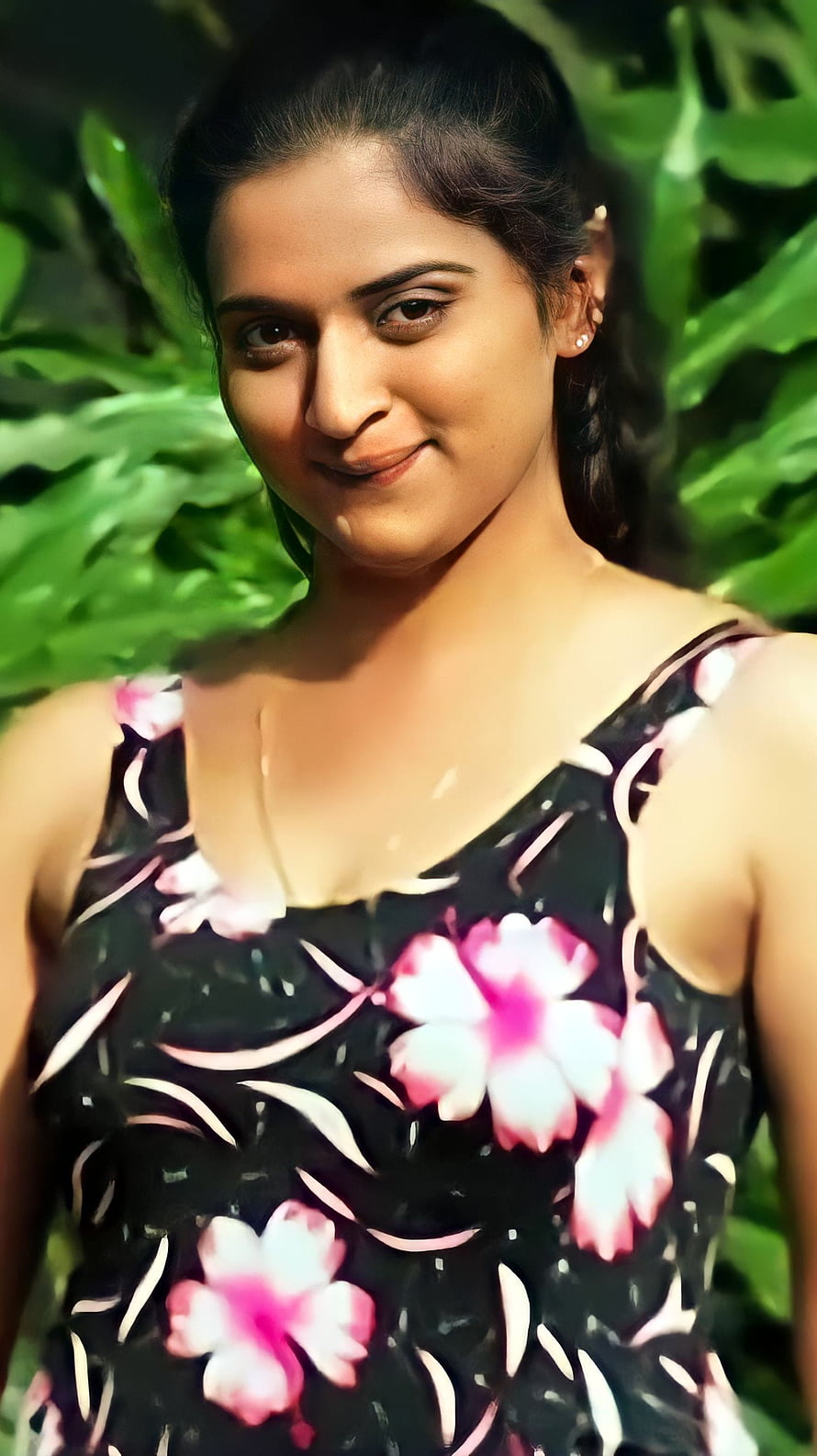 Pavitra Lokesh in a floral dress with a soft smile against a lush green leafy background HD phone wallpaper