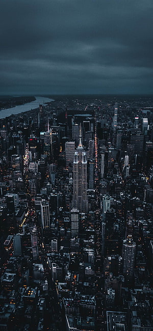 Aerial View of Manhattan Skyline at Night Featuring the Empire State Building Under Stormy Clouds HD phone wallpaper