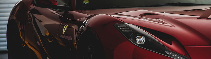 Close-up of a glossy red Ferrari front fender and headlight assembly HD wallpaper