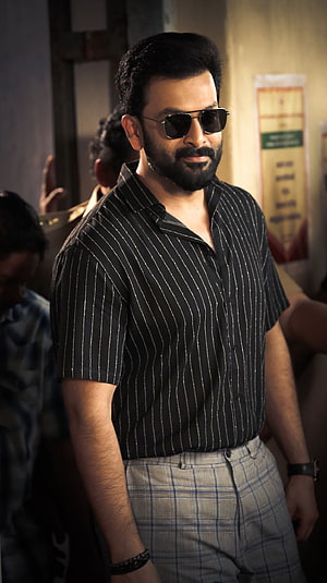 Prithviraj Sukumaran in a striped shirt and sunglasses from a Malayalam film HD phone wallpaper