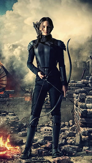 Katniss Everdeen in Black Armor Holding Bow Amidst Ruins and Fire HD phone wallpaper