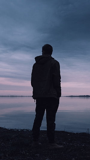 Solitary Figure Standing by a Calm Lake at Dusk HD phone wallpaper