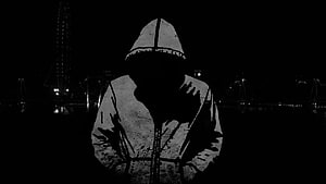 Silhouetted Figure in Hooded Garment Against Dark Nighttime Cityscape HD wallpaper