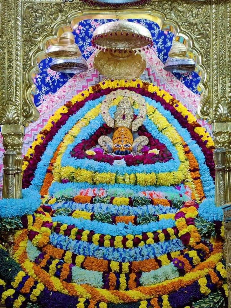 Shyam Baba adorned in vibrant concentric flower garlands within a golden temple shrine HD phone wallpaper