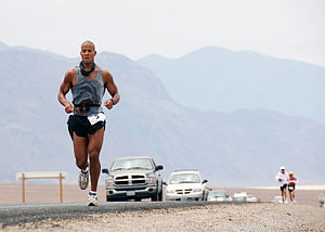 David Goggins Running on a Desert Road with Mountains in the Background HD wallpaper