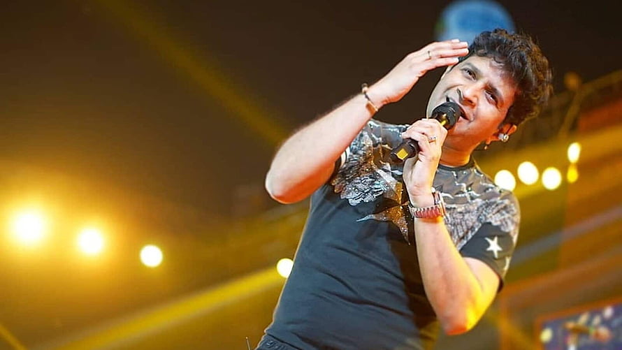 Krishnakumar Kunnath performing live on stage with microphone and warm concert lighting HD wallpaper