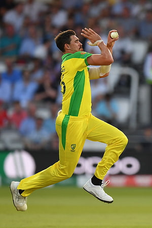 Mitchell Starc in Action During Cricket Match in Yellow and Green Uniform HD phone wallpaper