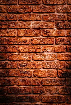 Warm Rustic Red Brick Wall Texture with Dramatic Lighting and Deep Shadows HD phone wallpaper