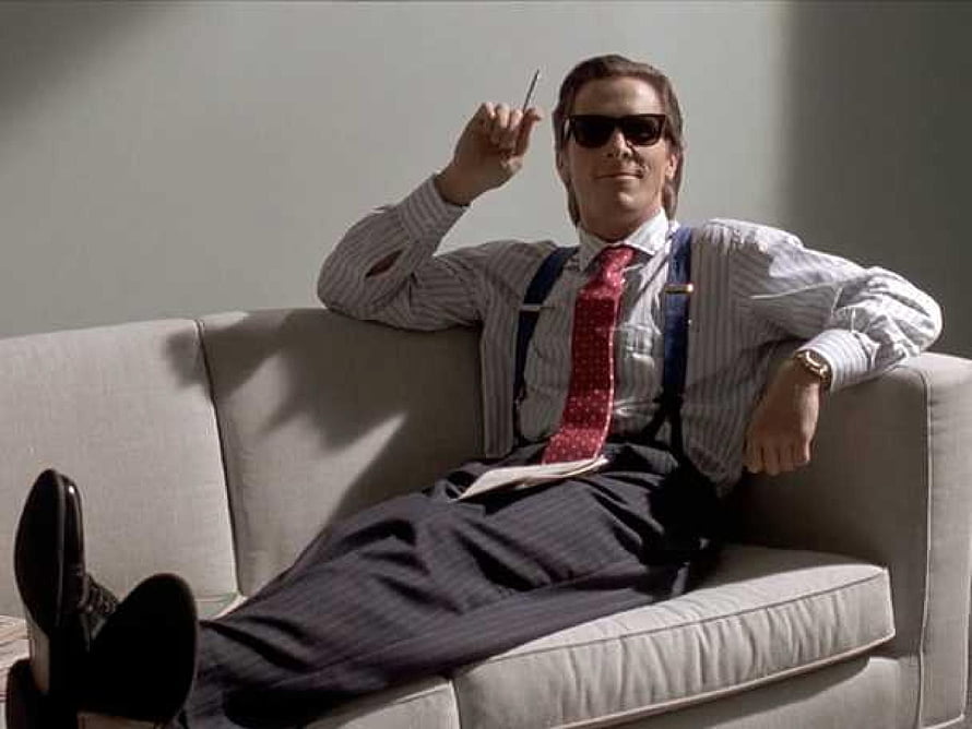 Patrick Bateman in American Psycho Reclining on a Sofa with Sunglasses and a Pen HD wallpaper