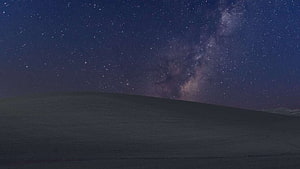 Milky Way Galaxy Arching Over a Dark Rolling Hill Under a Starry Night Sky HD wallpaper