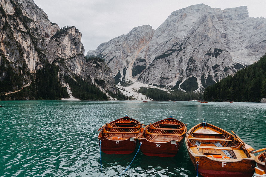 Wooden Boats Moored on a Turquoise Alpine Lake Surrounded by Dramatic Dolomite Peaks HD wallpaper