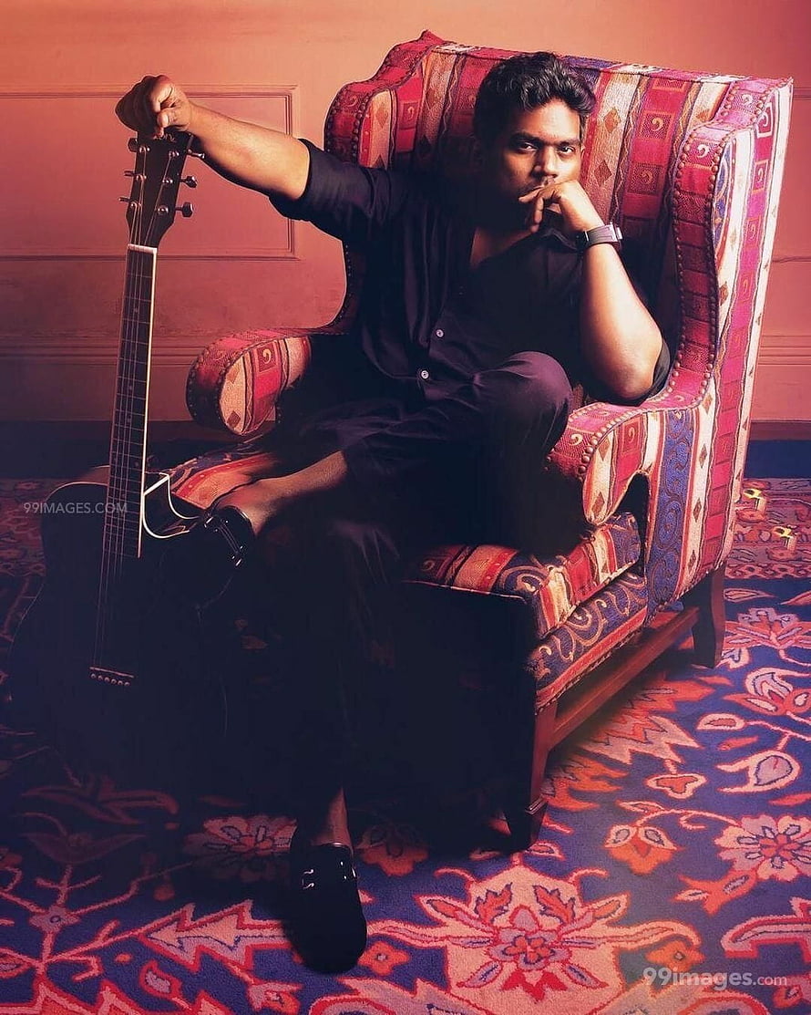 Yuvan Shankar Raja seated in a patterned armchair holding an acoustic guitar HD phone wallpaper