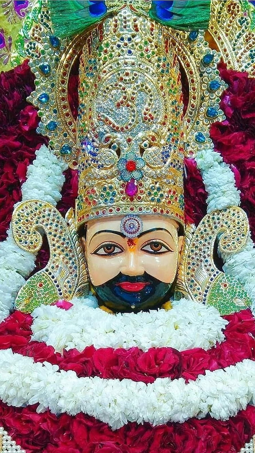 Khatu Shyam deity adorned in ornate jeweled crown and vibrant floral garlands HD phone wallpaper