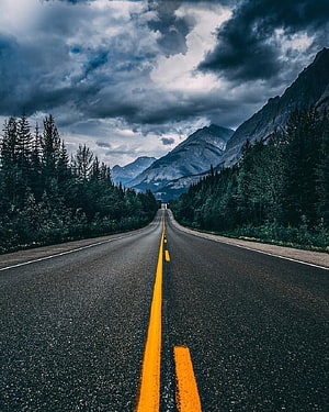 Dramatic Mountain Highway Under Stormy Skies with Pine Forests HD phone wallpaper