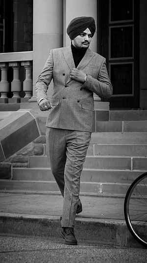 Sidhu Moose Wala in a double-breasted suit and turban walking down stone steps in a black and white portrait HD phone wallpaper