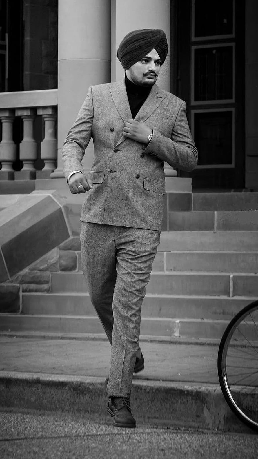 Sidhu Moose Wala in a double-breasted suit and turban walking down stone steps in a black and white portrait HD phone wallpaper