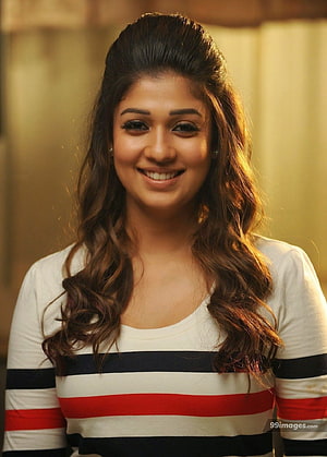 Nayanthara smiling portrait in striped top with warm golden background HD phone wallpaper