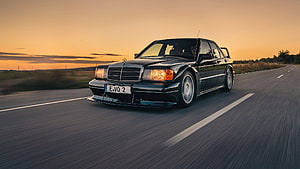 Black Mercedes-Benz 190E Evo 2 Sedan Driving on Open Road at Sunset HD wallpaper