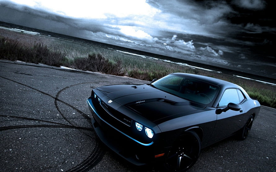 Black Dodge Challenger SRT8 Drifting on Coastal Road Under Stormy Sky HD wallpaper