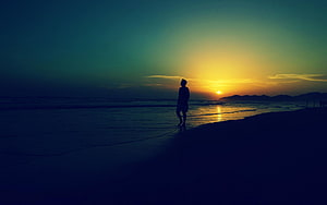Silhouette of a Man Standing on a Beach at Sunset HD wallpaper
