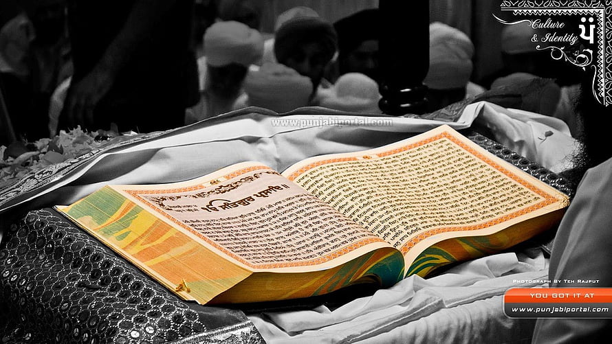 Open Guru Granth Sahib on ceremonial cloth with congregation in background HD wallpaper