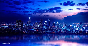 Downtown skyline at twilight with deep blue sky and city lights reflected in the water HD wallpaper