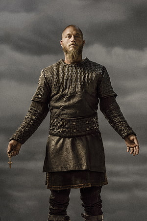 Ragnar Lothbrok in Viking Armor Holding a Cross Against a Stormy Sky HD phone wallpaper