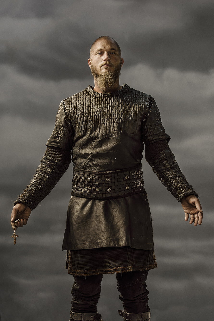 Ragnar Lothbrok in Viking Armor Holding a Cross Against a Stormy Sky HD phone wallpaper