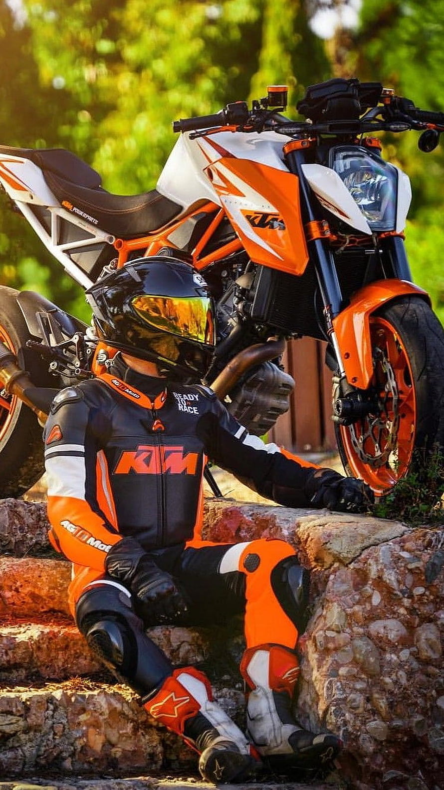 KTM Rider in Full Gear Sitting on Stone Steps Beside Orange and White Motorcycle HD phone wallpaper
