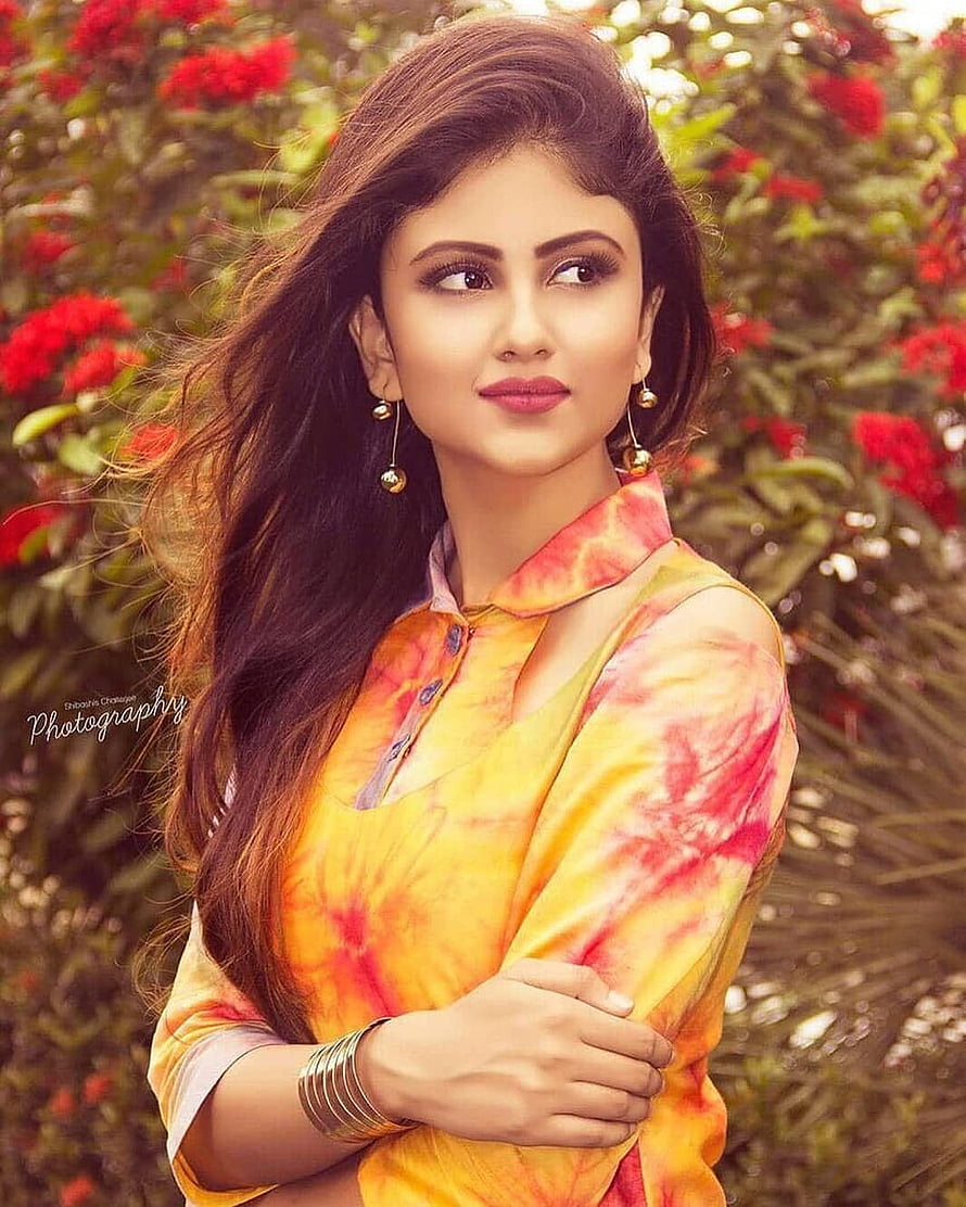 Portrait of a woman in a vibrant yellow and red tie-dye kurta with long wavy hair HD phone wallpaper