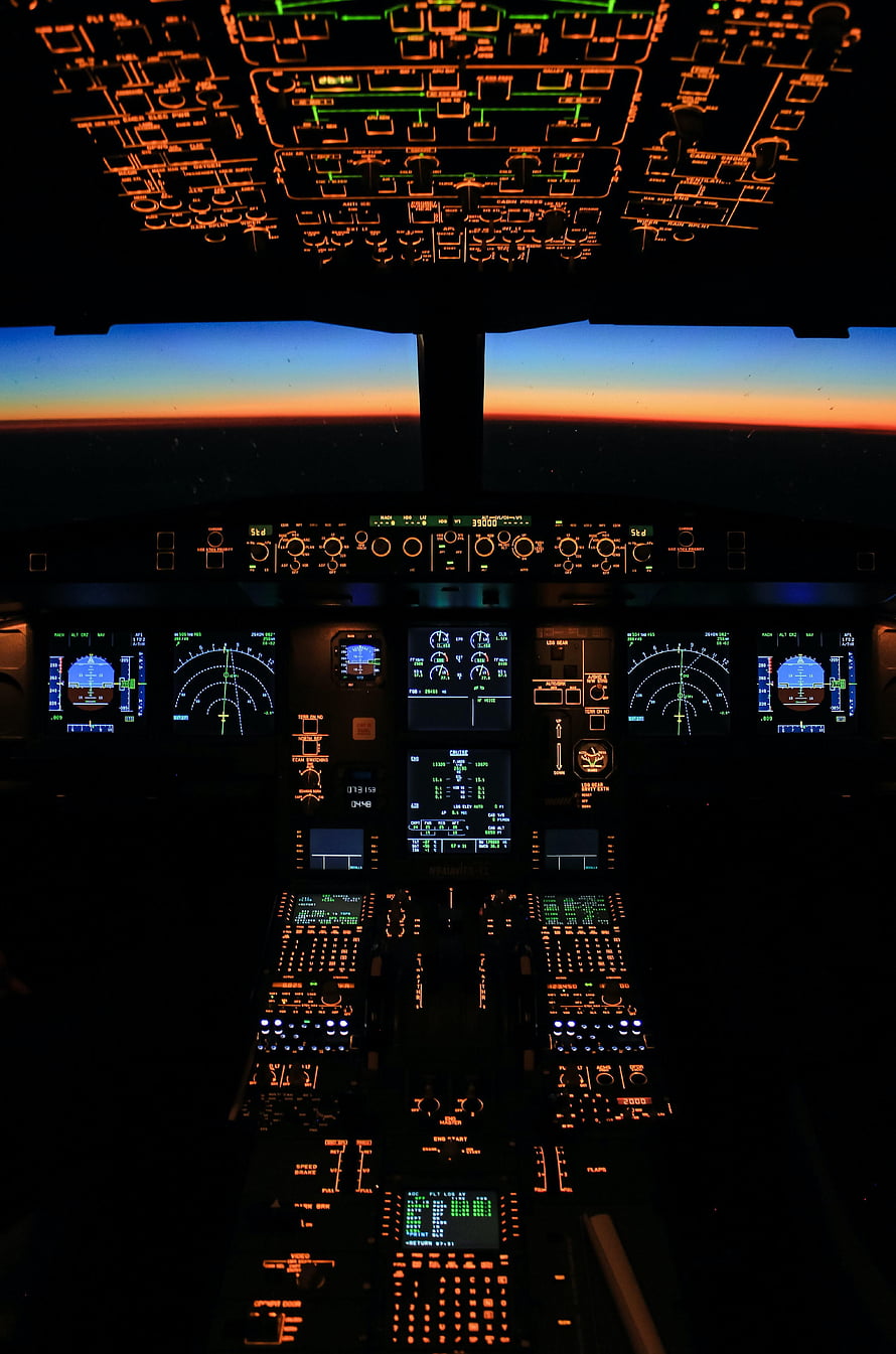 Commercial Airplane Cockpit Interior at Sunset with Glowing Instrument Panels and Overhead Controls HD phone wallpaper