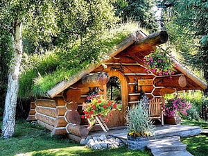 Charming Log Cabin Garden Shed with Mossy Green Roof and Vibrant Flower Arrangements HD wallpaper