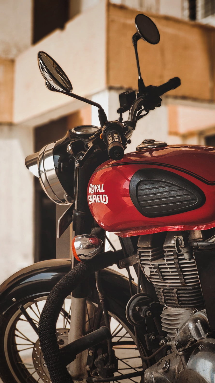 Close-up of a red Royal Enfield Bullet motorcycle parked in an urban setting HD phone wallpaper