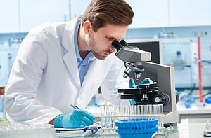 Male Scientist in White Lab Coat Using Microscope in Medical Laboratory HD wallpaper