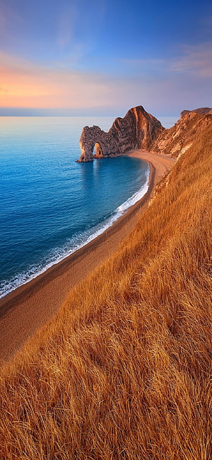 Golden Hour Coastal Cliffs and Sandy Beach with Turquoise Ocean Water HD phone wallpaper