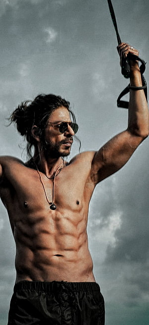 Shah Rukh Khan as Pathaan in a dramatic shirtless action pose with sunglasses and a necklace HD phone wallpaper