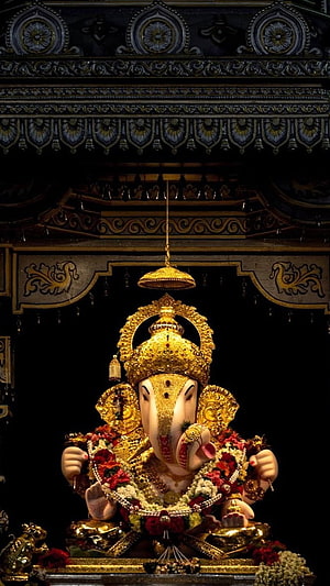 Dagdusheth Ganpati Murti Adorned in Gold and Flowers in a Dark Temple Setting HD phone wallpaper