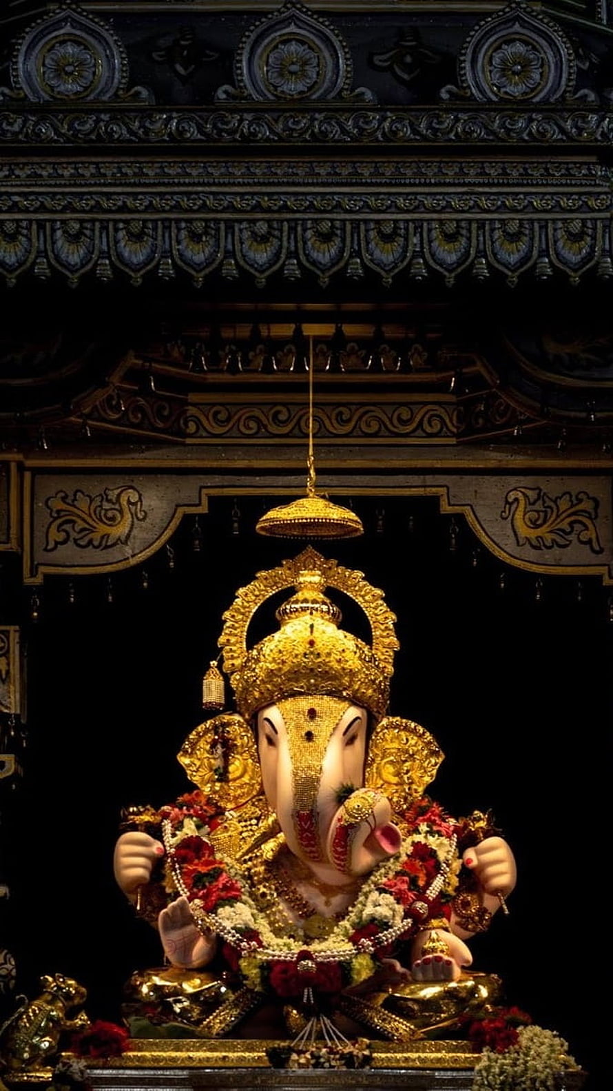 Dagdusheth Ganpati Murti Adorned in Gold and Flowers in a Dark Temple Setting HD phone wallpaper