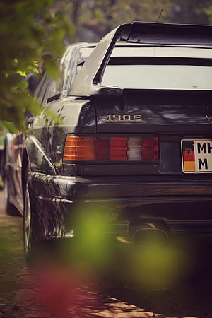 Rear View of a Classic Black Mercedes 190E with Prominent Spoiler and Taillights HD phone wallpaper